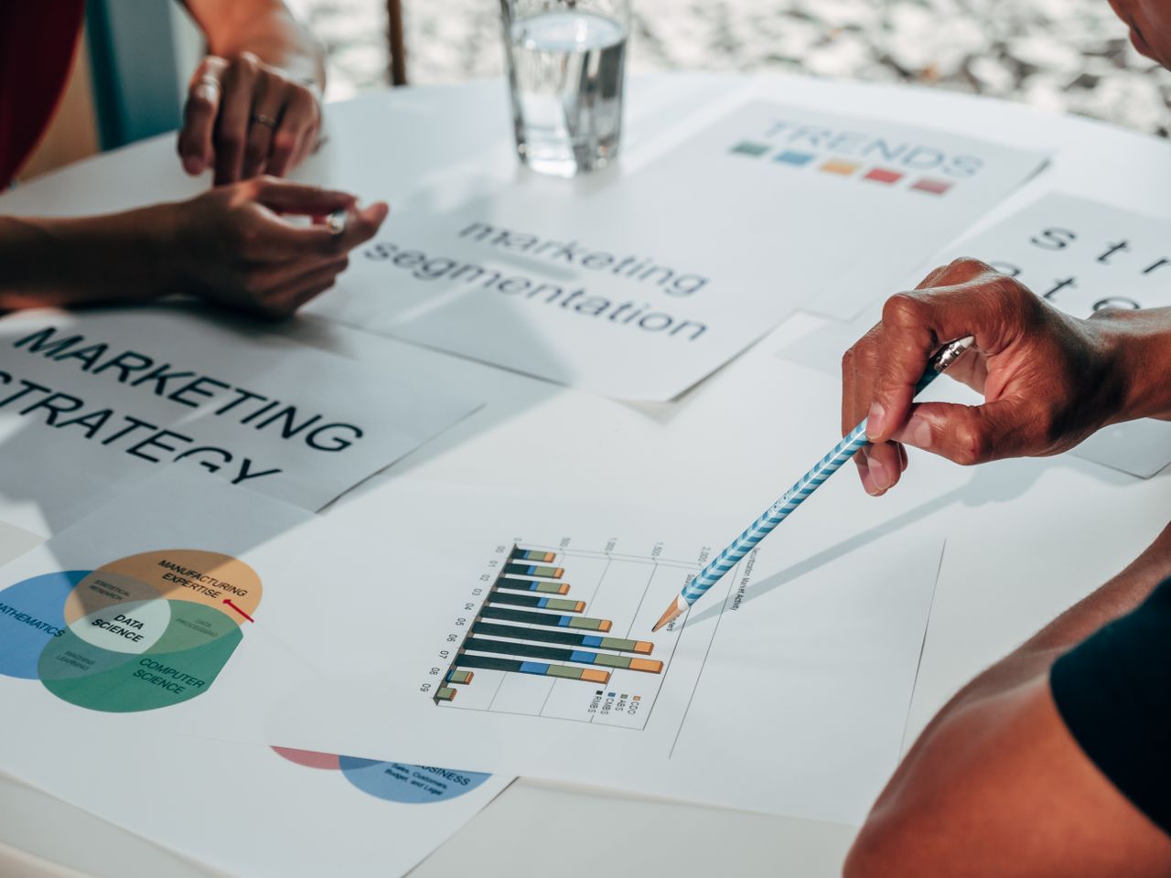 A team is working on marketing strategy in an office meeting, using data charts and papers.